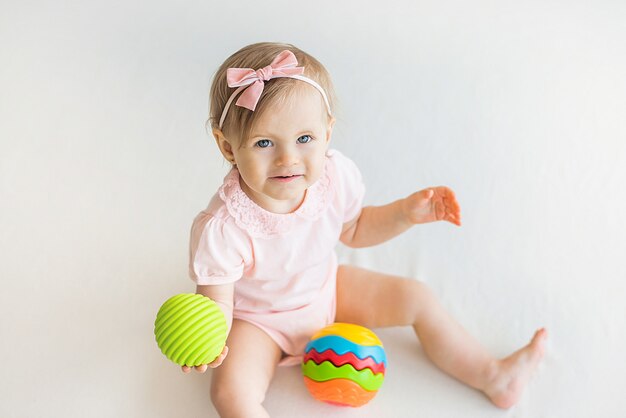 Glückliches Kinderzimmerbaby, das mit buntem Gummiball zu Hause spielt