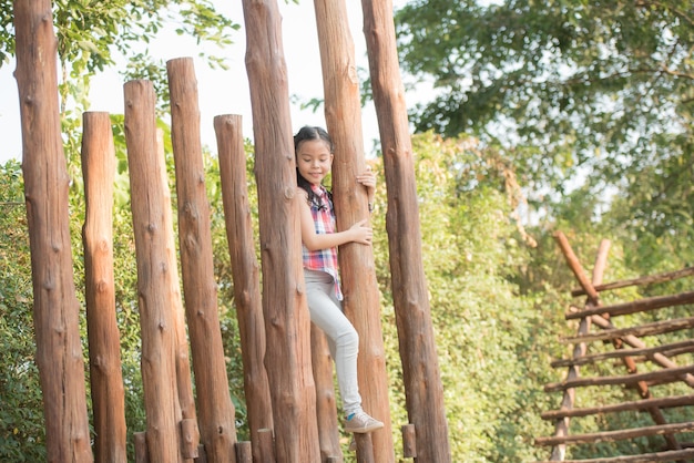 Glückliches kleines asiatisches Mädchenkind, das Spaß hat, auf dem Spielplatz in der Sommerzeit mit Lächeln zu spielen und gesundes, lustiges lächelndes Gesicht entzückendes reizendes weibliches Kind zu lachen.