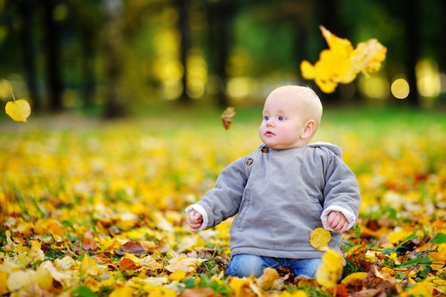 Glückliches kleines Baby, das Spaß im Herbstpark hat