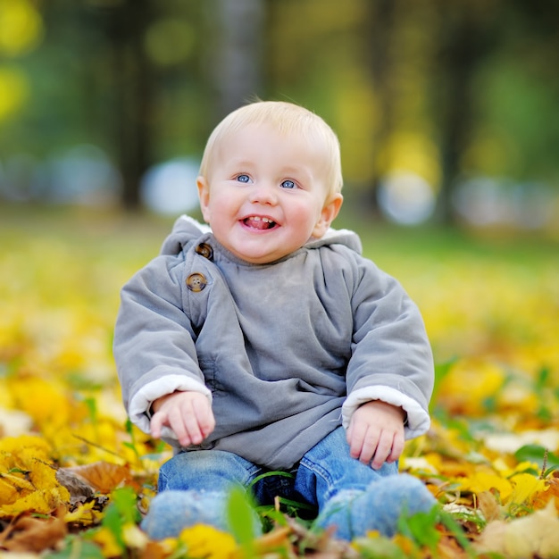 Glückliches kleines Baby, das Spaß im Herbstpark hat