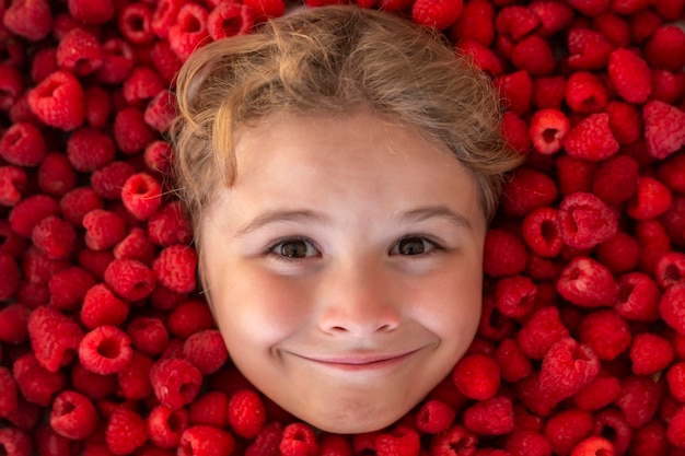 Glückliches kleines Kindergesicht mit Himbeerkinderpflücken Himbeerkinder pflücken frisches Obst auf organischer Raspel