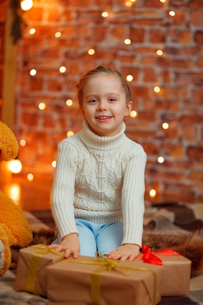 Glückliches kleines lächelndes Mädchen mit Weihnachtsgeschenkbox.