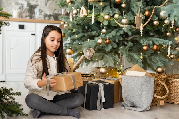 Glückliches kleines lächelndes Mädchen mit Weihnachtsgeschenkbox.