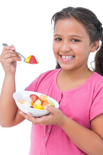 Glückliches kleines Mädchen, das Fruchtsalat isst
