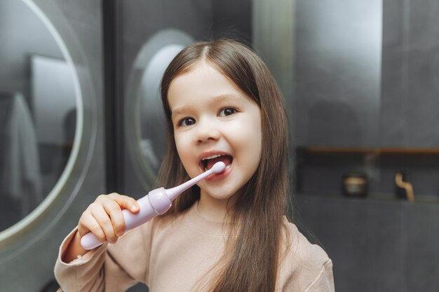 Glückliches kleines Mädchen, das ihre Zähne vor einem Badezimmerspiegel putzt Morgenhygiene