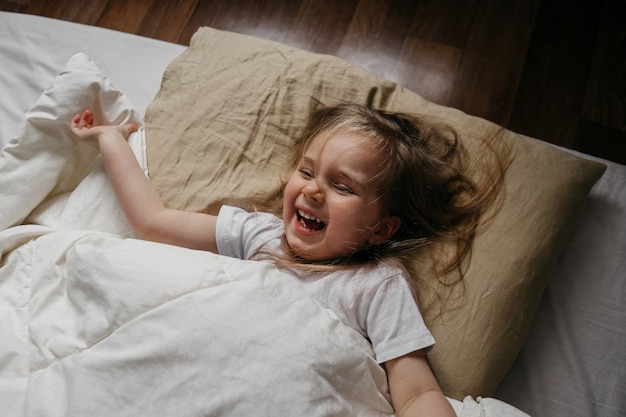 Foto glückliches kleines mädchen, das im bett liegt und lächelt und lacht