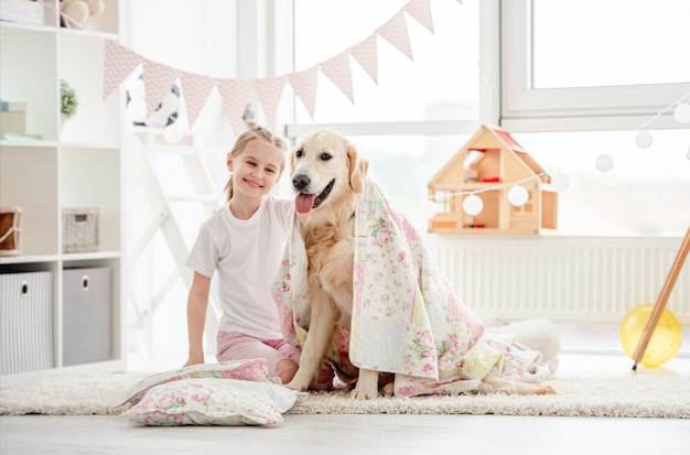 Glückliches kleines Mädchen, das mit einem schönen Hund spielt