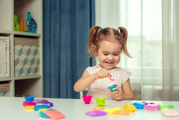 Glückliches kleines mädchen formt plastilin und lernt