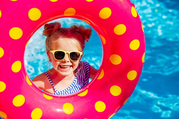 glückliches kleines Mädchen hält im Sommer einen Schwimmkreis in den Händen