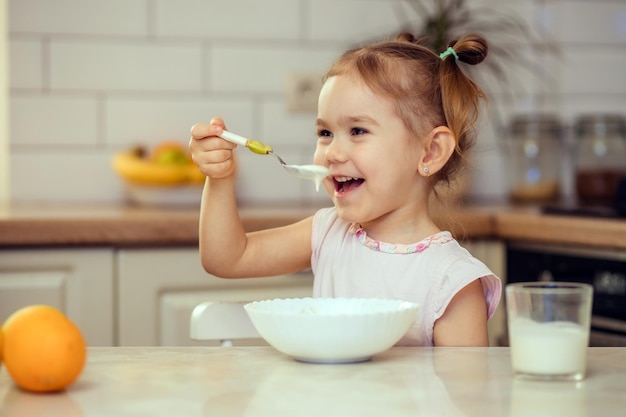 Glückliches kleines Mädchen im Alter von 23 Jahren isst zu Hause oder im Kindergarten gesundes Essen