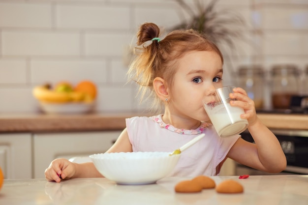 Glückliches kleines Mädchen im Alter von 23 Jahren isst zu Hause oder im Kindergarten gesundes Essen