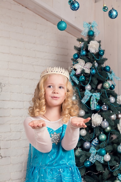 Glückliches kleines Mädchen im Kleid mit Geschenk haben Weihnachten