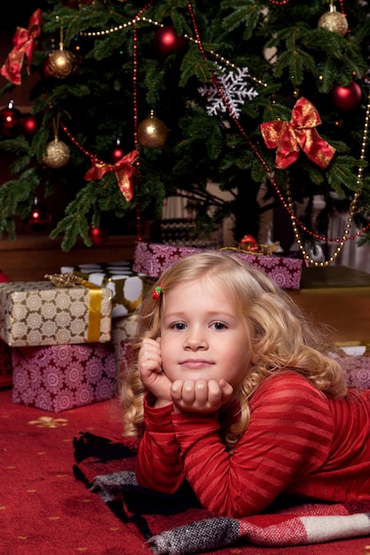 Glückliches kleines Mädchen im Kleid mit haben ein Weihnachtsgeschenk