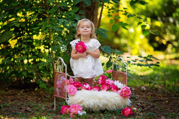 Foto glückliches kleines mädchen im retro-prinzessinnen-outfit im bett mit rosa blumen draußen im sommer