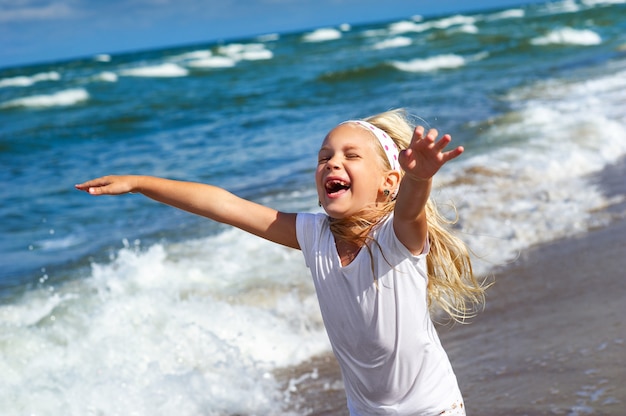 Glückliches kleines Mädchen in Kleidung am Ostseestrand auf der Kurischen Nehrung in Litauen