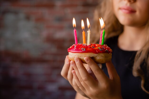 Glückliches kleines Mädchen macht einen Wunsch und bläst Kerzen auf einem Kuchen an ihrem Geburtstag aus