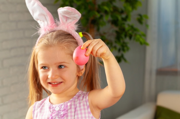 Glückliches kleines Mädchen malte gerade ein Ei für Ostern