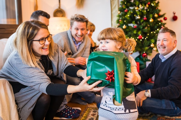 Glückliches kleines Mädchen mit Familie Unboxing Geschenk am Weihnachtstag