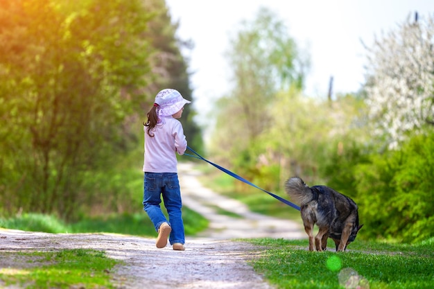 Glückliches kleines Mädchen mit Hund, der auf dem Land läuft