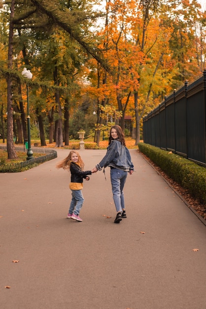 glückliches kleines Mädchen mit Schwester im Park im Herbst