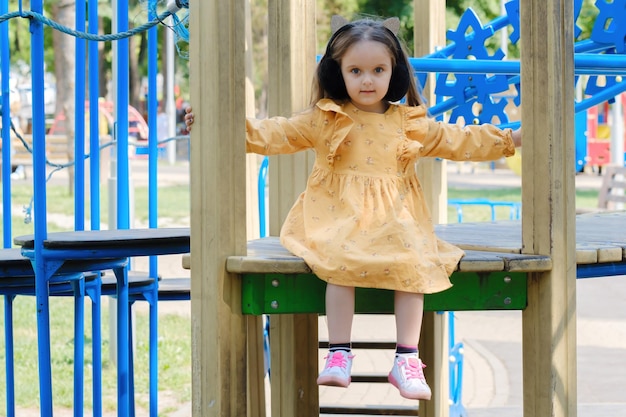 Glückliches kleines Mädchen spielt auf dem Spielplatz im Park