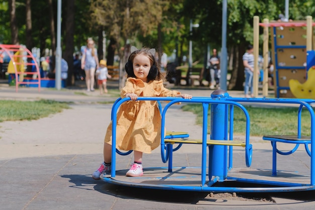 Glückliches kleines Mädchen spielt auf dem Spielplatz im Park