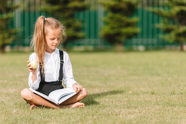 Glückliches kleines Schulmädchen mit einer Tafel im Freien