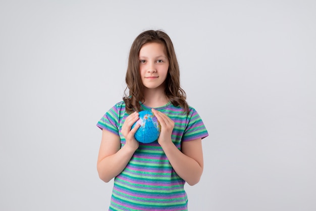 Glückliches kleines Schulmädchen mit Globus auf ihrer Hand