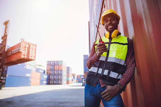 Glückliches Lächeln des Porträtpersonals, das im Logistikhafen der Frachtschifffahrt arbeitet und die Funksteuerung hält