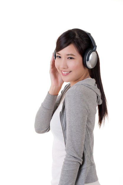 Glückliches lächelndes asiatisches Mädchen mit Kopfhörern, Musikkonzeptporträt auf weißem Hintergrund.