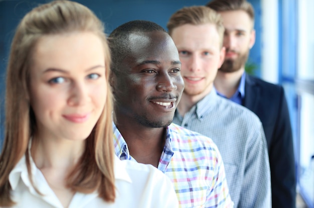 Foto glückliches lächelndes geschäftsteam, das im büro in einer reihe steht