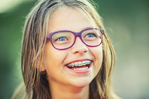 Foto glückliches lächelndes mädchen mit zahnspangen junges süßes kaukasisches blondes mädchen, das zahnspangen trägt