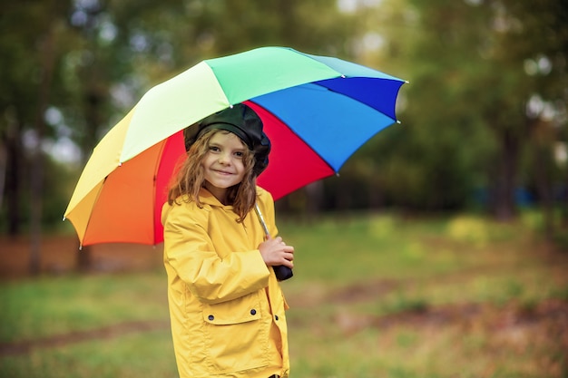 Glückliches lustiges Kindermädchen mit Regenschirm in den Gummistiefeln