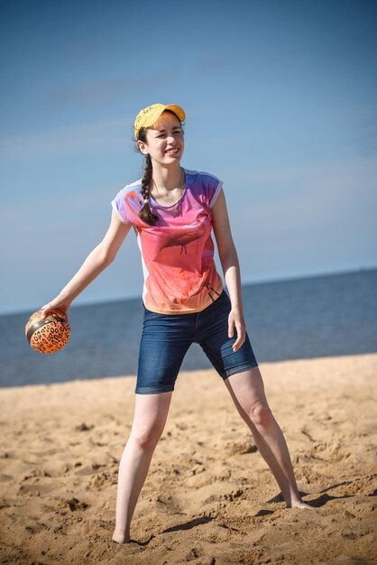 Glückliches Mädchen am Strand beim Ballspielen