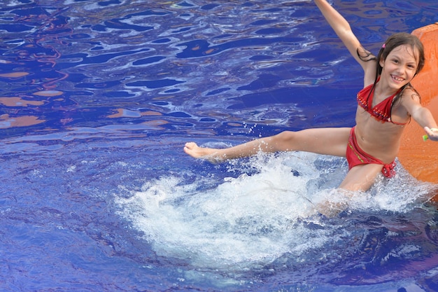 Glückliches Mädchen auf Wasserrutsche im Sommer