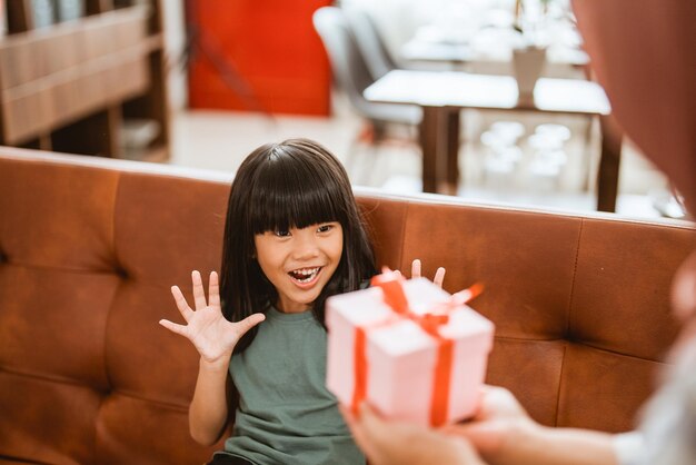 Glückliches Mädchen, das ein neues Geschenk von Mama bekommt