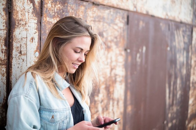 Foto glückliches mädchen, das ihr smartphone allein hält und benutzt - kaukasische frau, die mit ihrem telefon spielt - tausendjährige 20er jahre