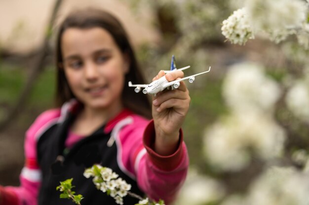 Glückliches Mädchen, das mit Spielzeugflugzeug im Garten spielt