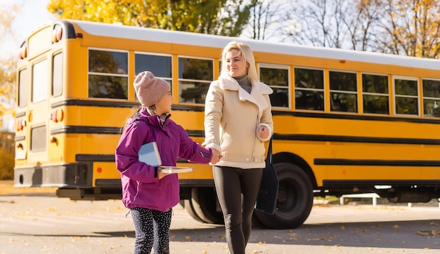 Glückliches Mädchen, das Mutter mit dem Schulbus anschaut.
