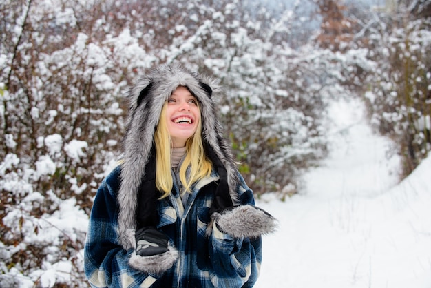 Glückliches Mädchen, das Schneewintertag Winterferien schöne Frau in warmem Mantelpelzhut und -handschuhen spielt