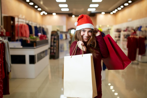Glückliches Mädchen einkaufen Geschenke im Einkaufszentrum auf Weihnachtsverkauf Neujahr Urlaub einkaufen Idee Konzept lächelnd