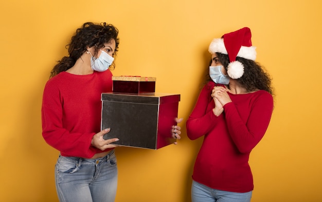 Glückliches Mädchen erhält Weihnachtsgeschenke von einem Freund auf Gelb