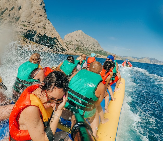 Glückliches Mädchen fährt im Urlaub auf dem Meer mit einem Bananenboot und macht ein Selfie