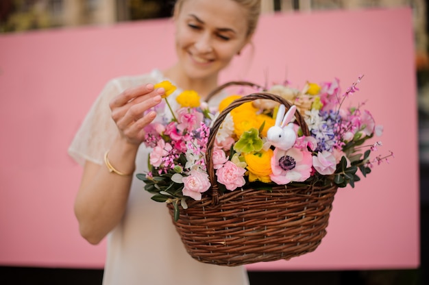 Glückliches Mädchen hält Blumenstrauß im Blumenkorb