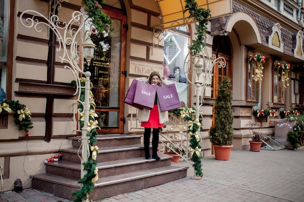 Foto glückliches mädchen hält papiertüten mit verkaufssymbol in den geschäften mit verkäufen zu weihnachten