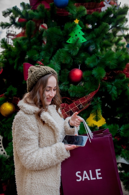 Foto glückliches mädchen hält papiertüten mit verkaufssymbol in den geschäften mit verkäufen zu weihnachten