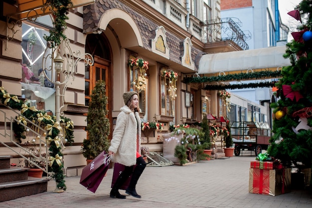 Glückliches Mädchen hält Papiertüten mit Verkaufssymbol in den Geschäften mit Verkäufen zu Weihnachten
