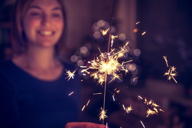 Glückliches Mädchen hält zur Weihnachtszeit eine Wunderkerze