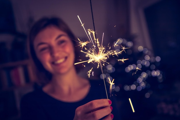 Glückliches Mädchen hält zur Weihnachtszeit eine Wunderkerze