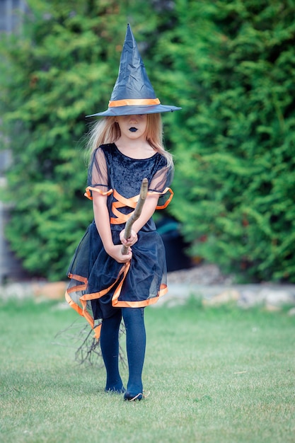 Glückliches Mädchen im Halloween-Kostüm mit Steckfassungskürbis. Süßes sonst gibt's Saures